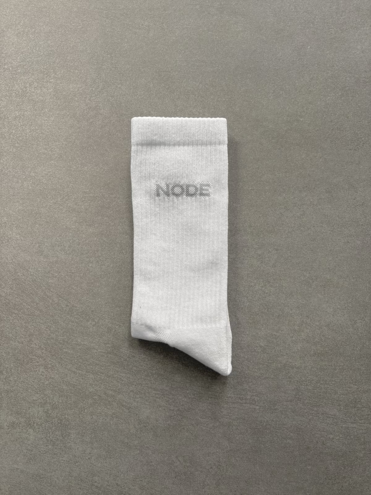 White sock with 'NODE' branding on a grey background